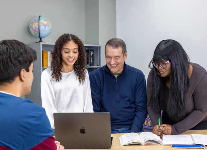 Oakton students and faculty gathered around a laptop.